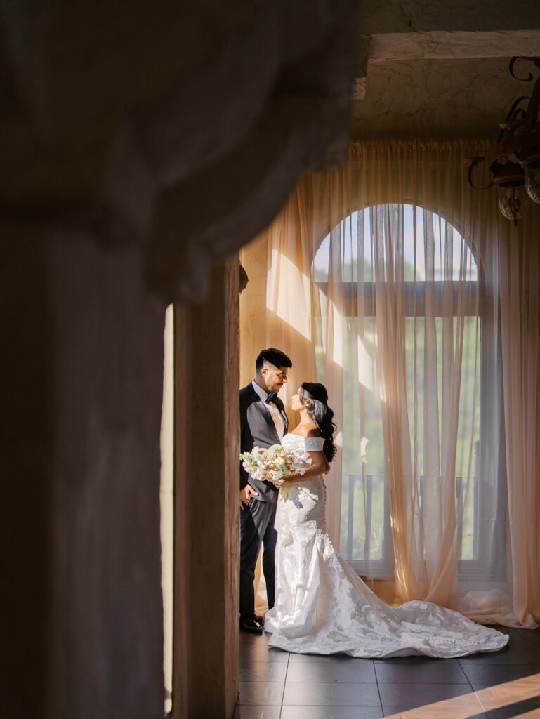 Groom in black tux walking with bride through arches at Villa Antonia, wedding editorial on film