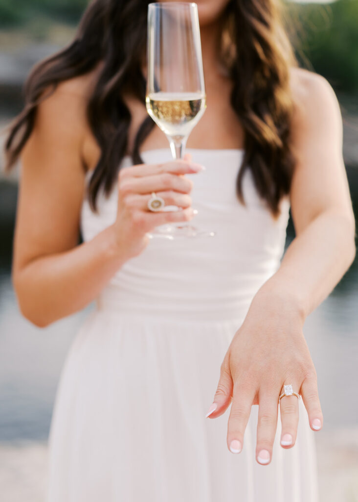 Lake Travis proposal photography featuring a couple popping champagne by the lakeside after saying yes.