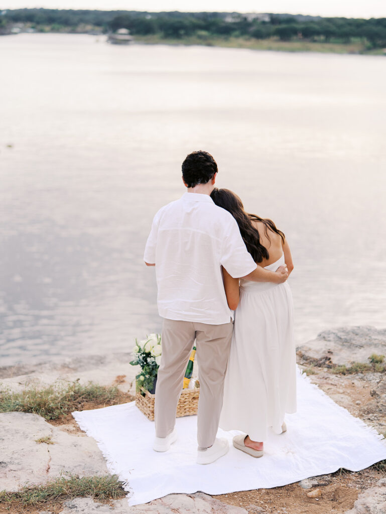Lake Travis proposal photography featuring a couple popping champagne by the lakeside after saying yes.