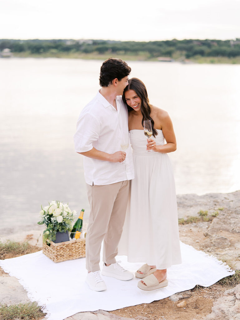 Lake Travis proposal photography featuring a couple popping champagne by the lakeside after saying yes.