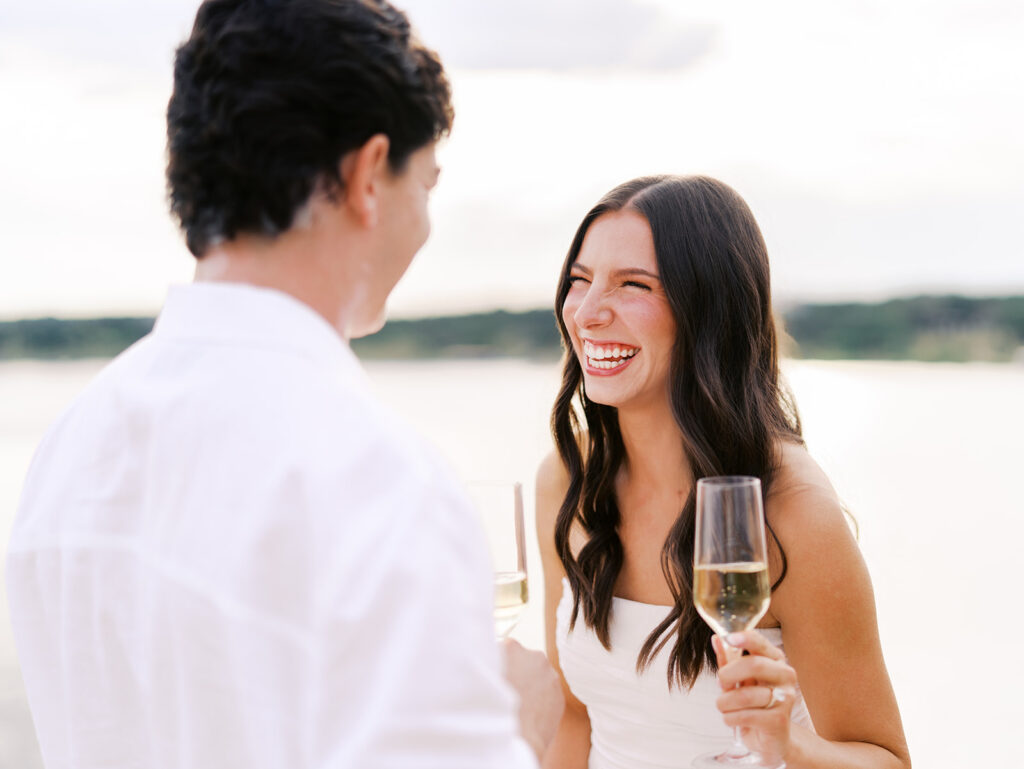 Lake Travis proposal photography featuring a couple popping champagne by the lakeside after saying yes.