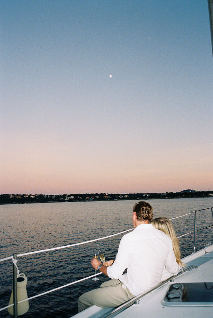 Dreamy Lake Travis sailboat engagement photo featuring the couple under a glowing summer moon.