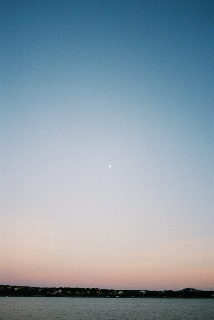 Dreamy Lake Travis sailboat engagement photo featuring the couple under a glowing summer moon.
