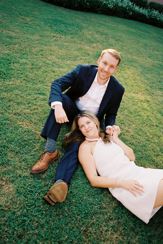 Emma and Luke smiling together in the Grand Galvez garden under tall palm trees captured on film with soft, natural light and timeless color.
