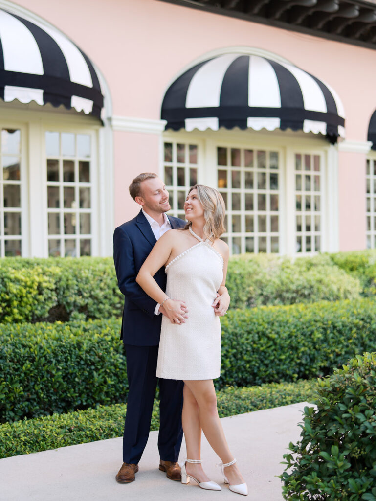 Emma and Luke smiling together in the Grand Galvez garden under tall palm trees captured on film with soft, natural light and timeless color.