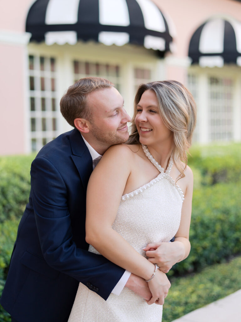 Emma and Luke smiling together in the Grand Galvez garden under tall palm trees captured on film with soft, natural light and timeless color.