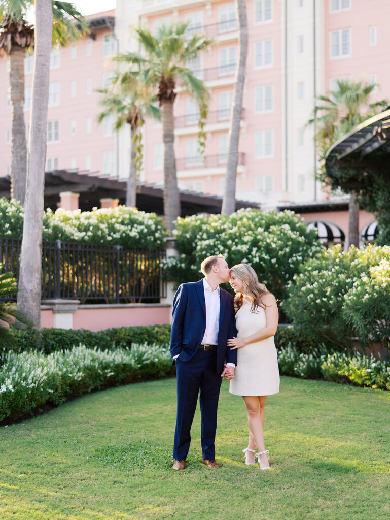 Emma and Luke smiling together in the Grand Galvez garden under tall palm trees captured on film with soft, natural light and timeless color.