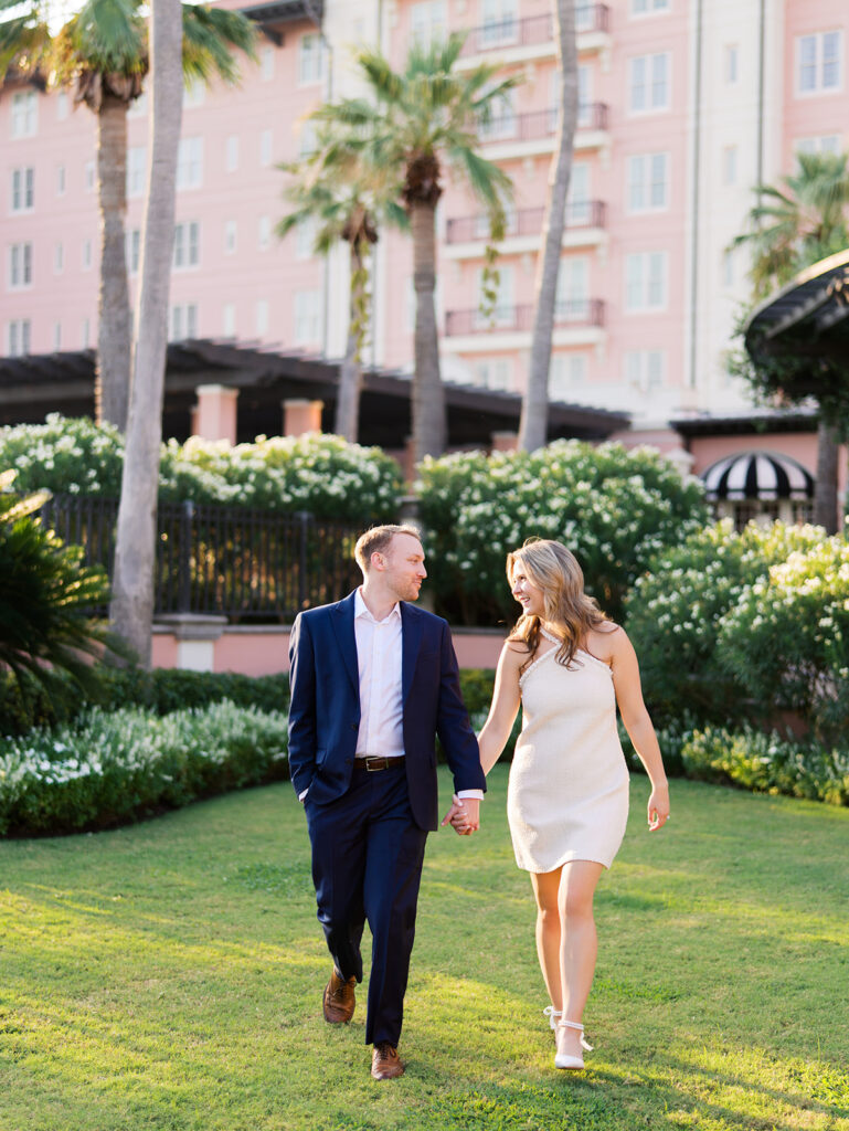 Emma and Luke smiling together in the Grand Galvez garden under tall palm trees captured on film with soft, natural light and timeless color.