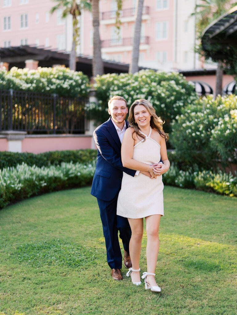 Emma and Luke smiling together in the Grand Galvez garden under tall palm trees captured on film with soft, natural light and timeless color.