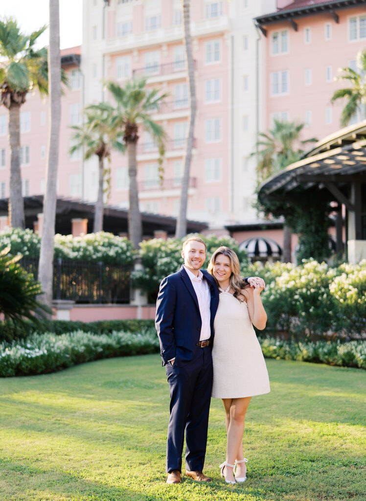 Emma and Luke smiling together in the Grand Galvez garden under tall palm trees captured on film with soft, natural light and timeless color.