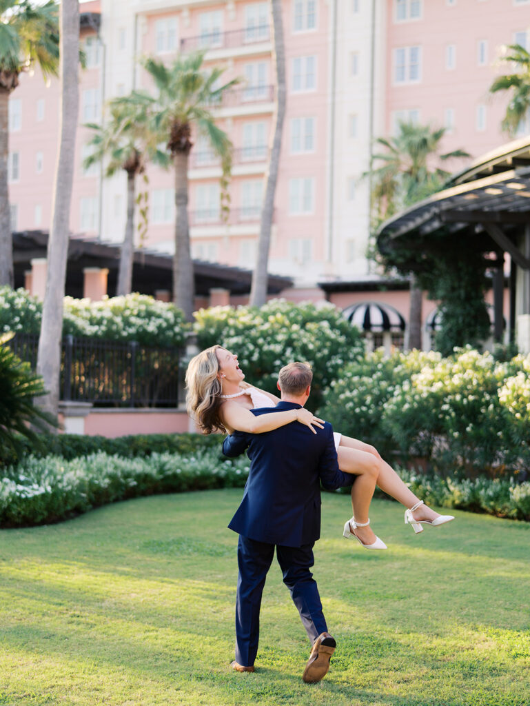 Emma and Luke smiling together in the Grand Galvez garden under tall palm trees captured on film with soft, natural light and timeless color.