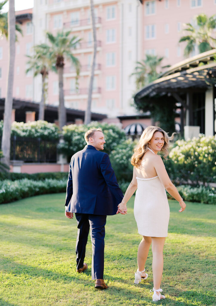 Emma and Luke smiling together in the Grand Galvez garden under tall palm trees captured on film with soft, natural light and timeless color.