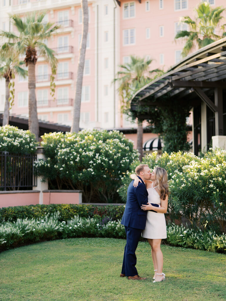 Emma and Luke smiling together in the Grand Galvez garden under tall palm trees captured on film with soft, natural light and timeless color.
