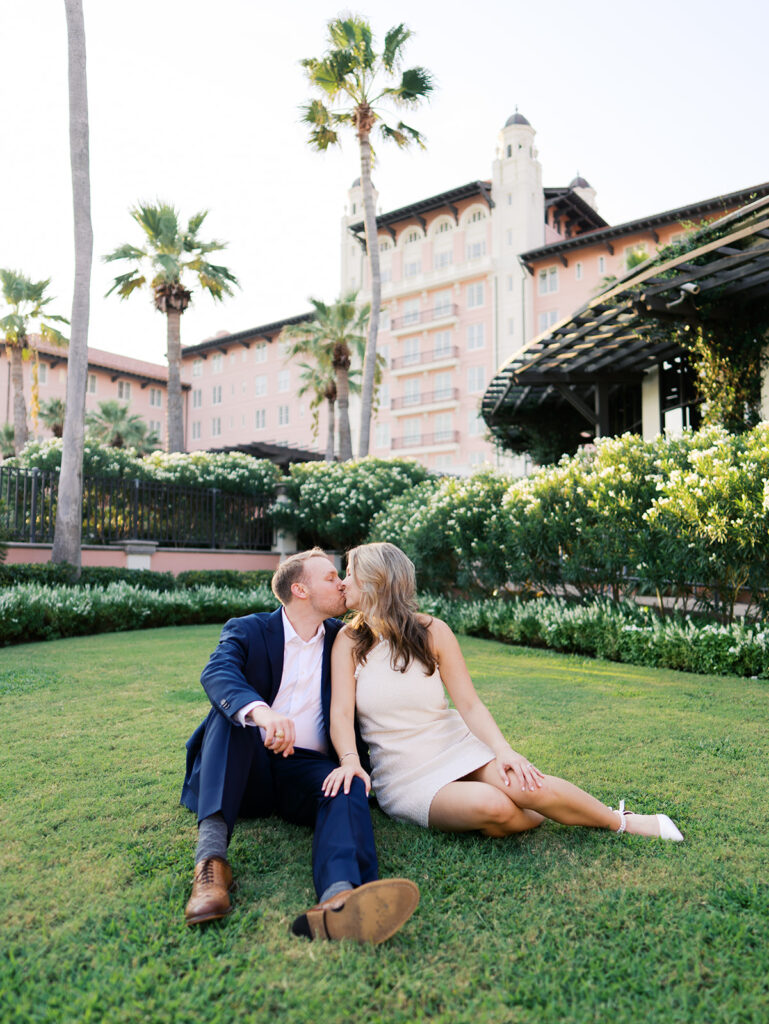 Emma and Luke smiling together in the Grand Galvez garden under tall palm trees captured on film with soft, natural light and timeless color.