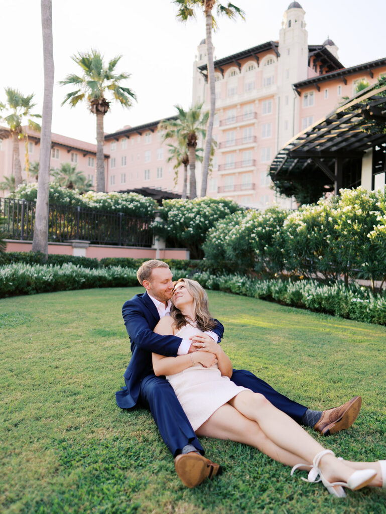 Emma and Luke smiling together in the Grand Galvez garden under tall palm trees captured on film with soft, natural light and timeless color.