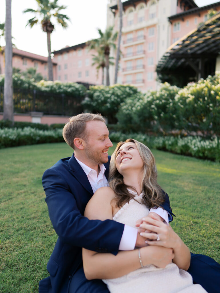 Emma and Luke smiling together in the Grand Galvez garden under tall palm trees captured on film with soft, natural light and timeless color.