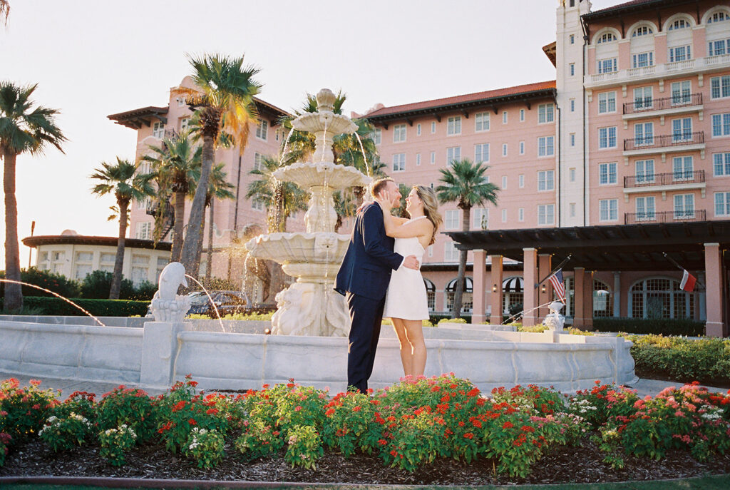 Candid laughter by the ocean at golden hour during Emma and Luke’s film engagement session at the Grand Galvez.