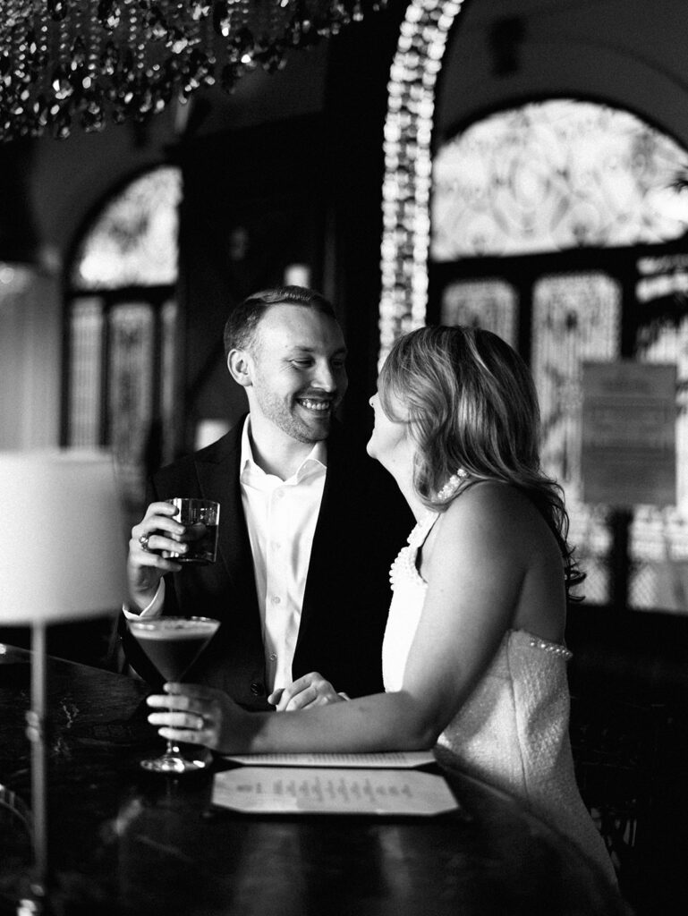 Emma and Luke cheersing and enjoying cocktails at the Grand Galvez bar photographed on film with a relaxed, romantic vibe