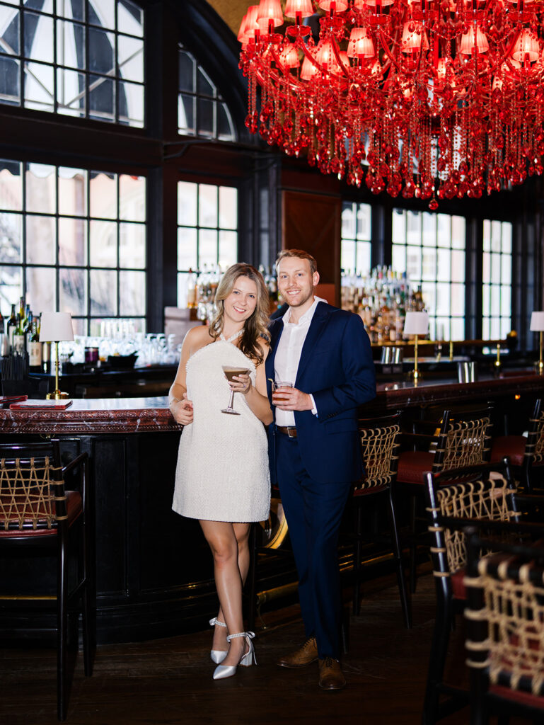 Emma and Luke cheersing and enjoying cocktails at the Grand Galvez bar photographed on film with a relaxed, romantic vibe