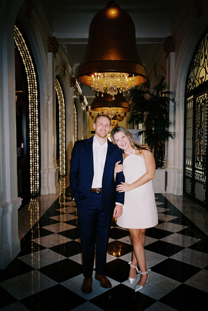 Emma and Luke cheersing and enjoying cocktails at the Grand Galvez bar photographed on film with a relaxed, romantic vibe