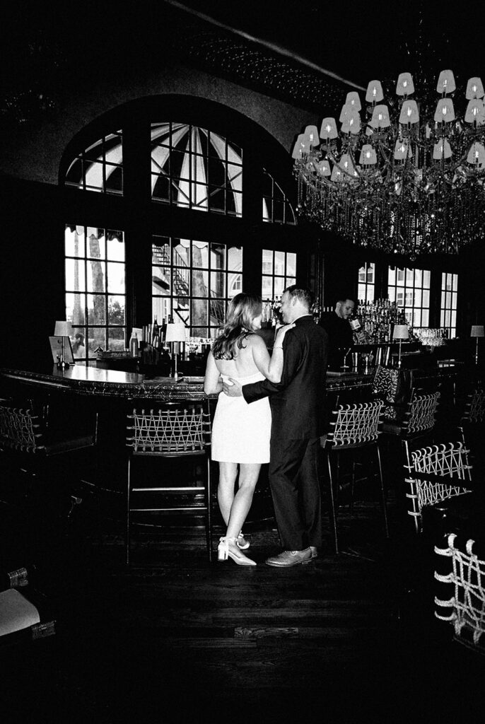 Emma and Luke cheersing and enjoying cocktails at the Grand Galvez bar photographed on film with a relaxed, romantic vibe