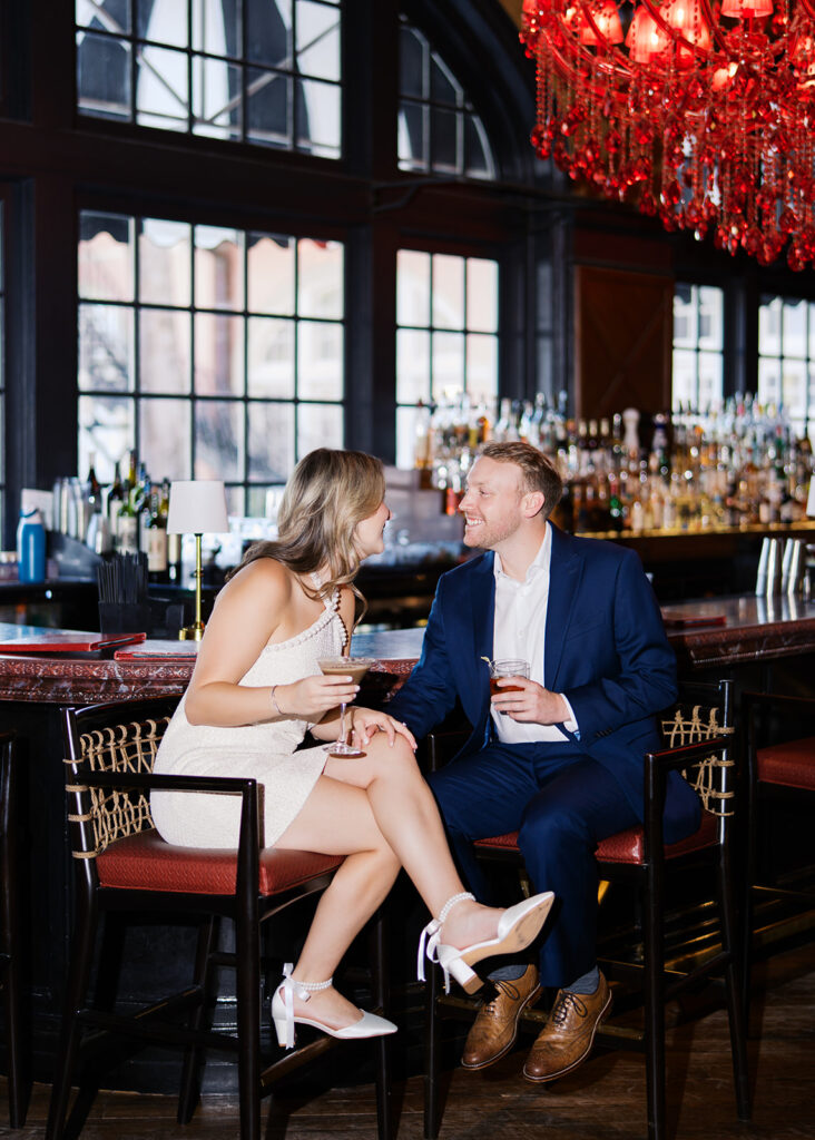 Emma and Luke cheersing and enjoying cocktails at the Grand Galvez bar photographed on film with a relaxed, romantic vibe