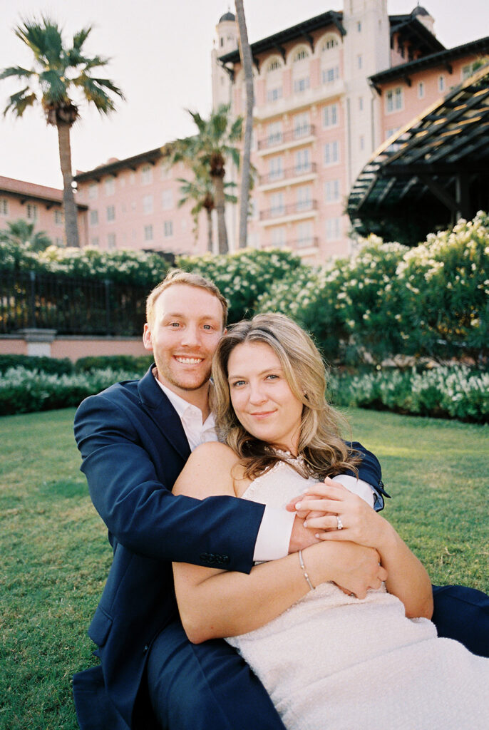 Emma and Luke smiling together in the Grand Galvez garden under tall palm trees captured on film with soft, natural light and timeless color.