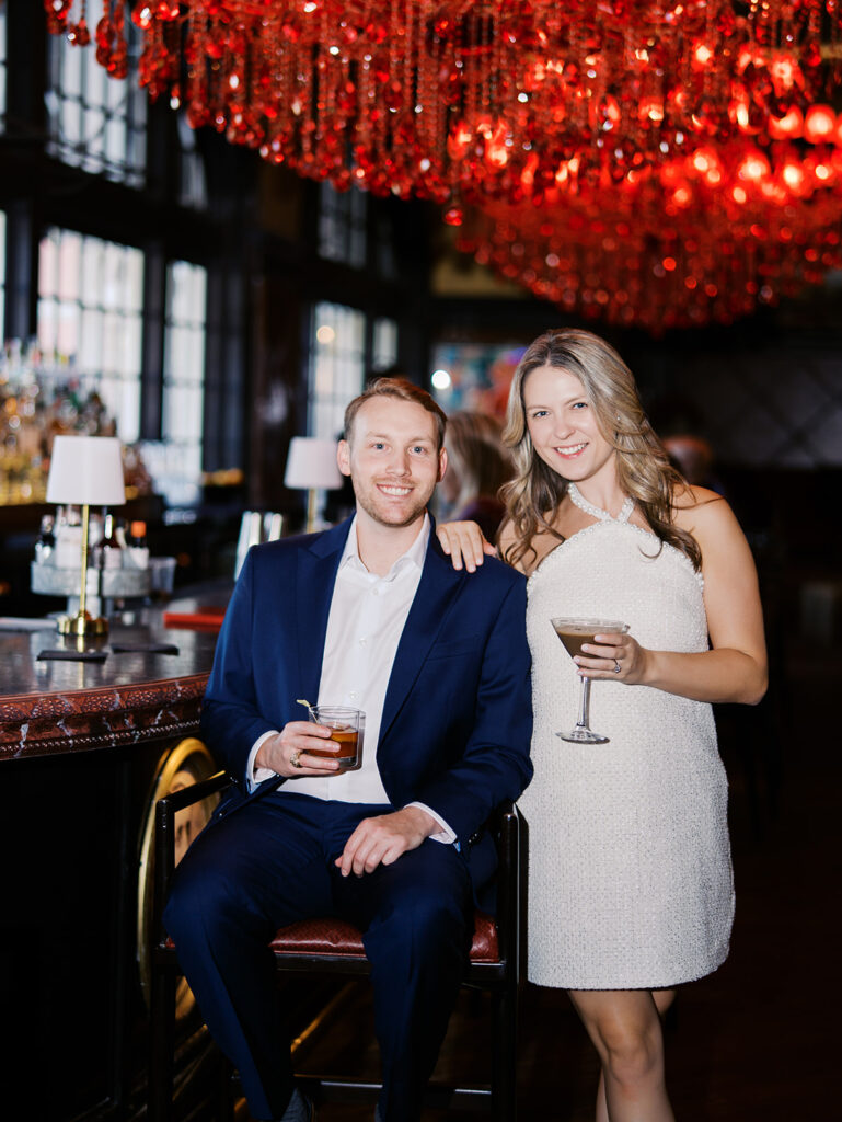 Emma and Luke cheersing and enjoying cocktails at the Grand Galvez bar photographed on film with a relaxed, romantic vibe