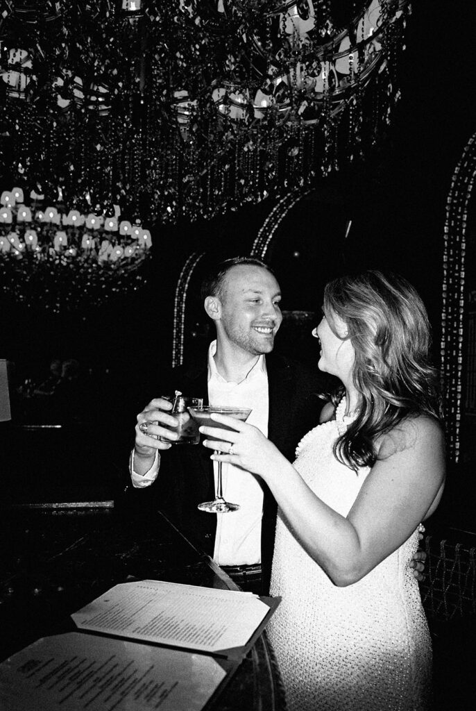 Emma and Luke cheersing and enjoying cocktails at the Grand Galvez bar photographed on film with a relaxed, romantic vibe