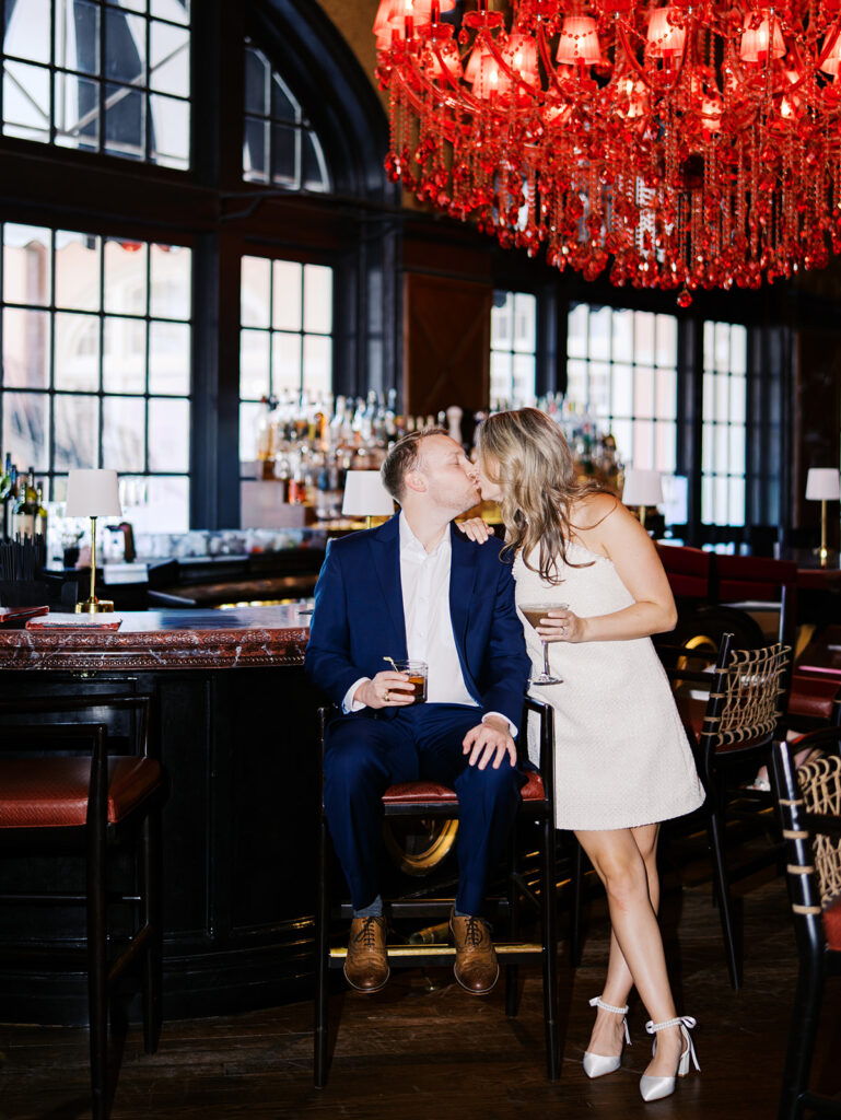 Emma and Luke cheersing and enjoying cocktails at the Grand Galvez bar photographed on film with a relaxed, romantic vibe