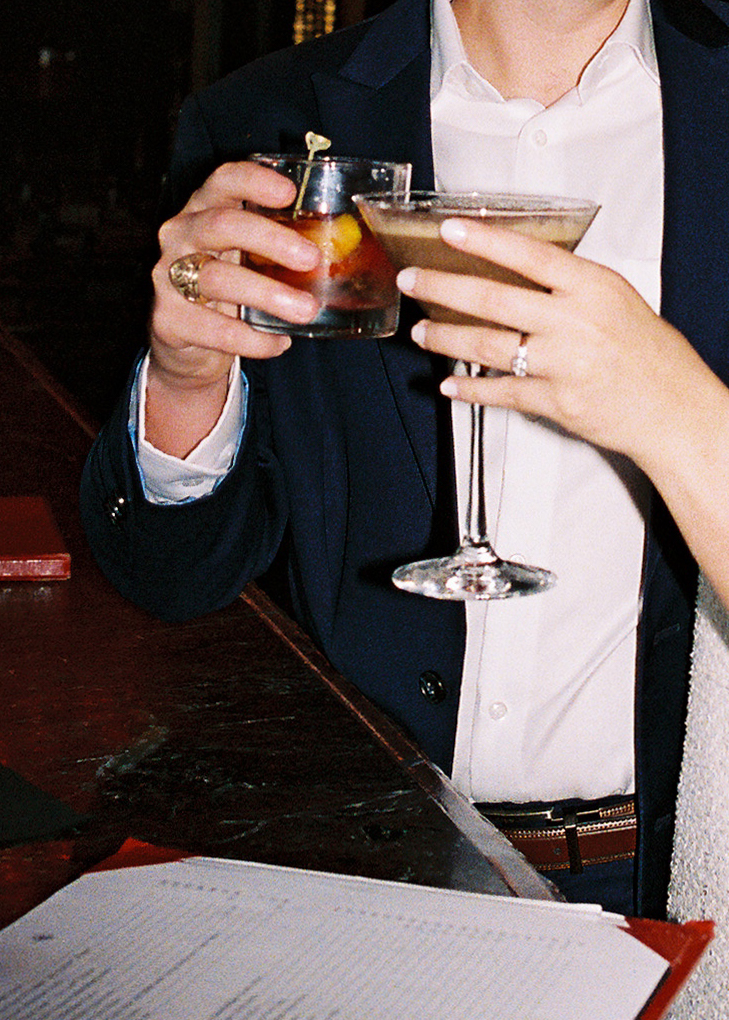 Emma and Luke cheersing and enjoying cocktails at the Grand Galvez bar photographed on film with a relaxed, romantic vibe