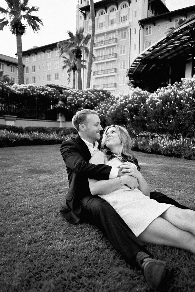 Emma and Luke smiling together in the Grand Galvez garden under tall palm trees captured on film with soft, natural light and timeless color.