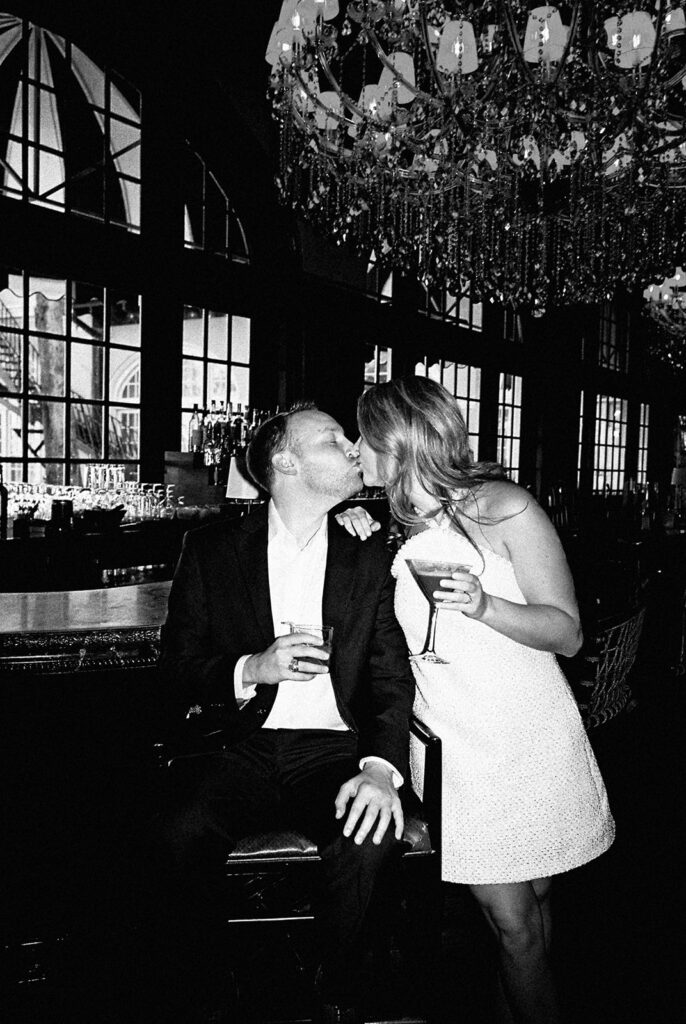 Emma and Luke cheersing and enjoying cocktails at the Grand Galvez bar photographed on film with a relaxed, romantic vibe