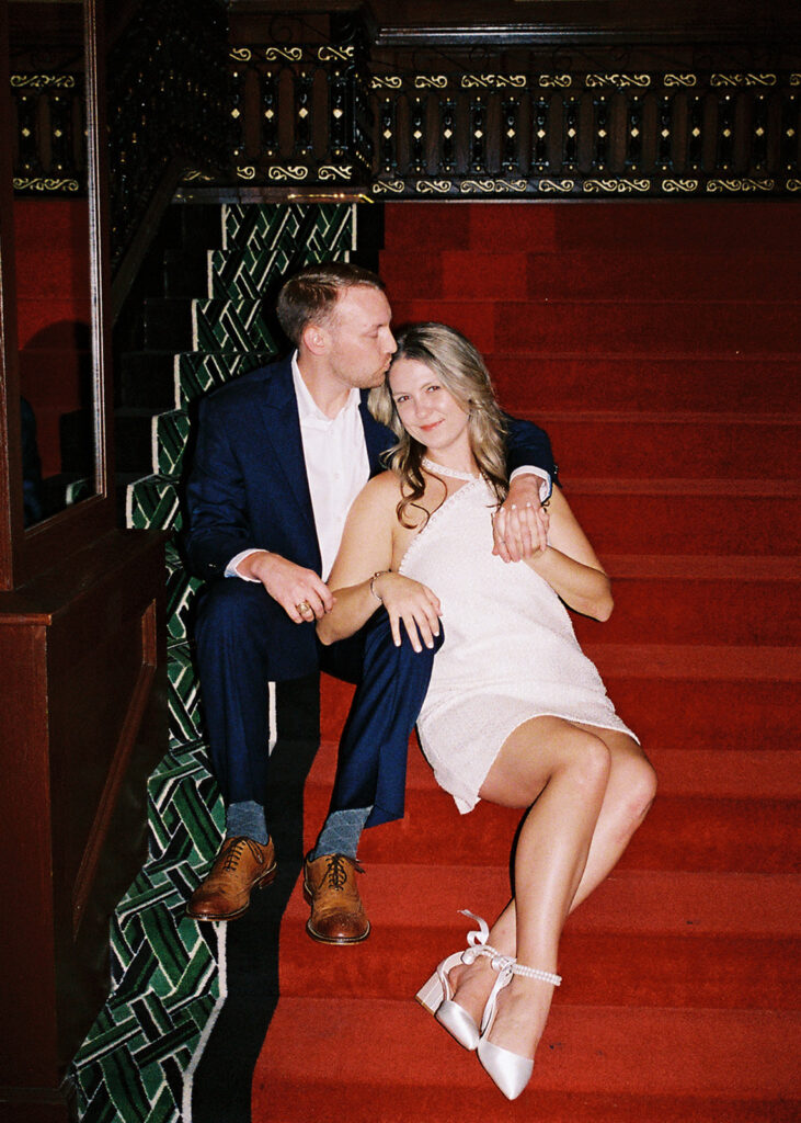 Emma and Luke cheersing and enjoying cocktails at the Grand Galvez bar photographed on film with a relaxed, romantic vibe