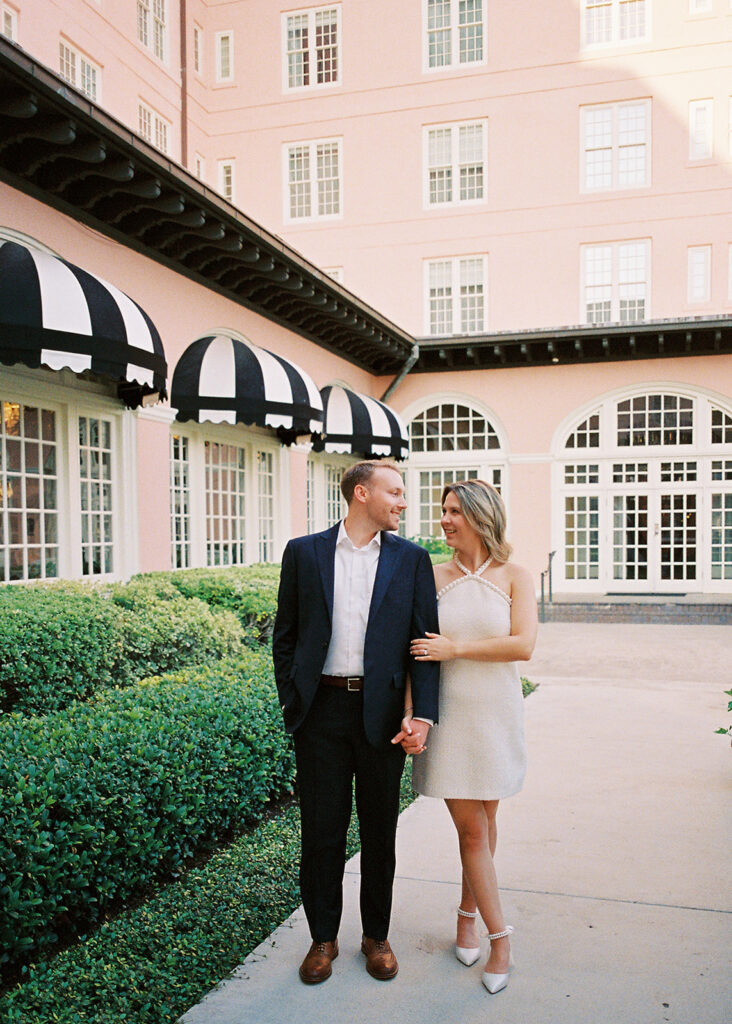 Emma and Luke smiling together in the Grand Galvez garden under tall palm trees captured on film with soft, natural light and timeless color.