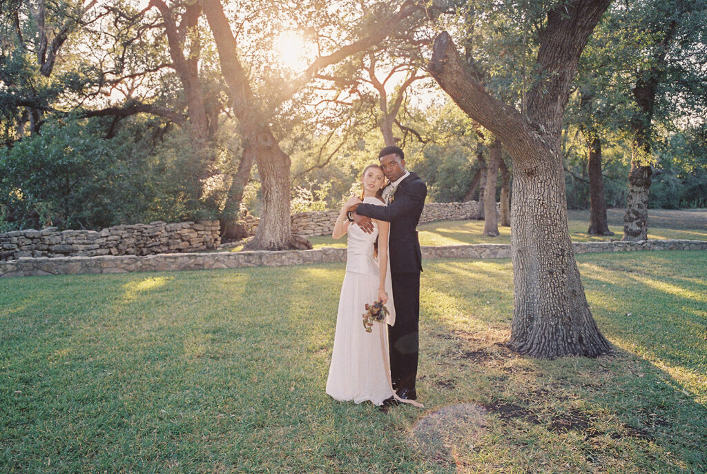 Bride and groom walking through The Addison Grove surrounded by golden fall foliage and lush florals