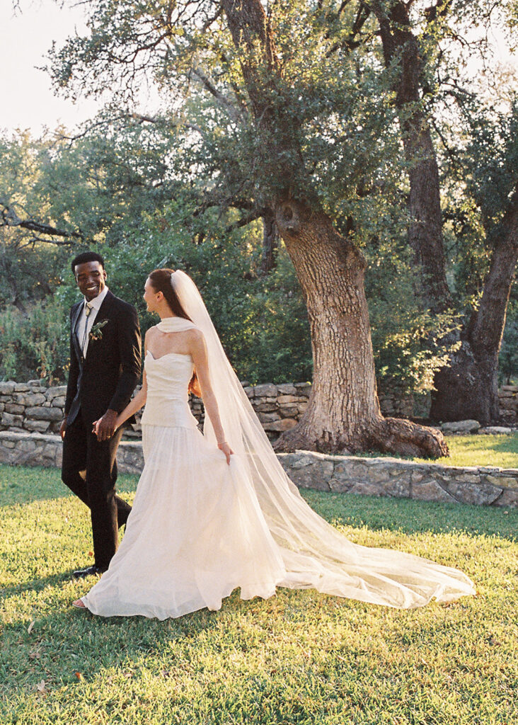 Bride and groom walking through The Addison Grove surrounded by golden fall foliage and lush florals