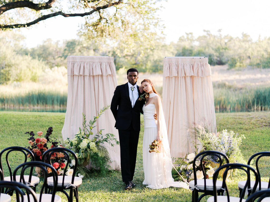 Bride and groom walking through The Addison Grove surrounded by golden fall foliage and lush florals