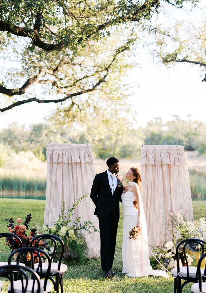 Bride and groom walking through The Addison Grove surrounded by golden fall foliage and lush florals