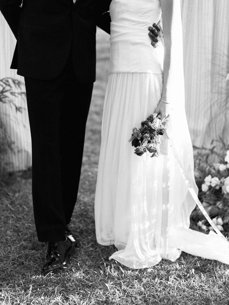 Bride and groom walking through The Addison Grove surrounded by golden fall foliage and lush florals