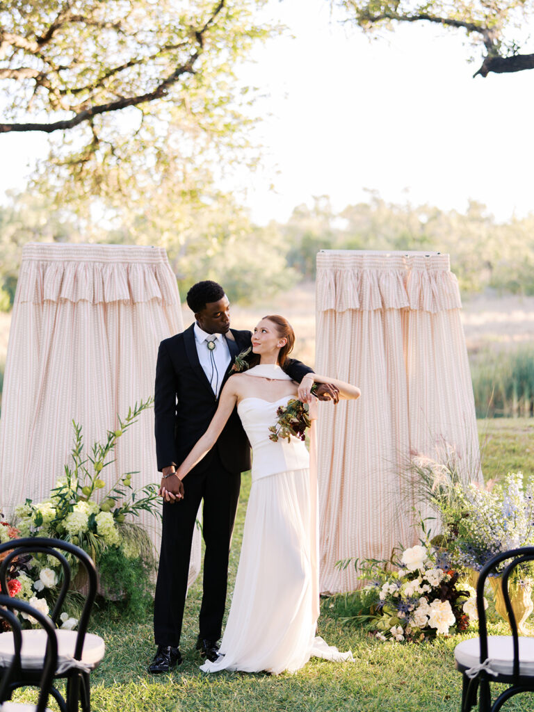 Bride and groom walking through The Addison Grove surrounded by golden fall foliage and lush florals