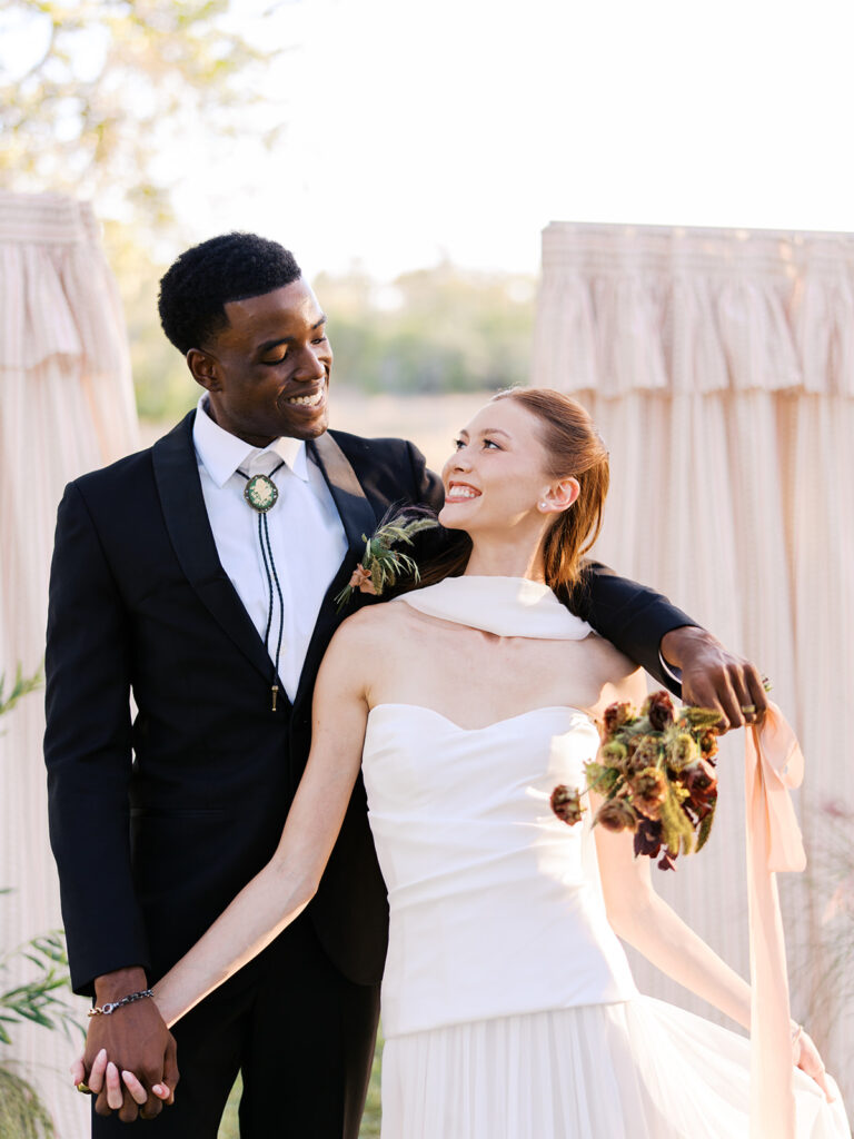 Bride and groom walking through The Addison Grove surrounded by golden fall foliage and lush florals