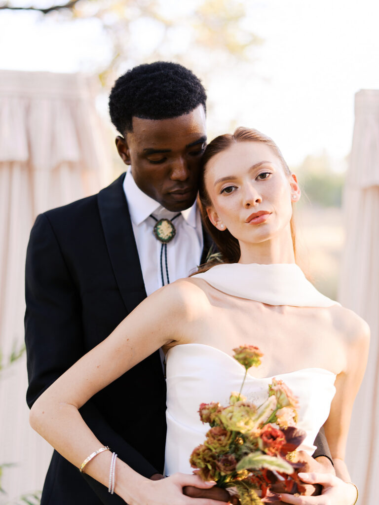 Bride and groom walking through The Addison Grove surrounded by golden fall foliage and lush florals