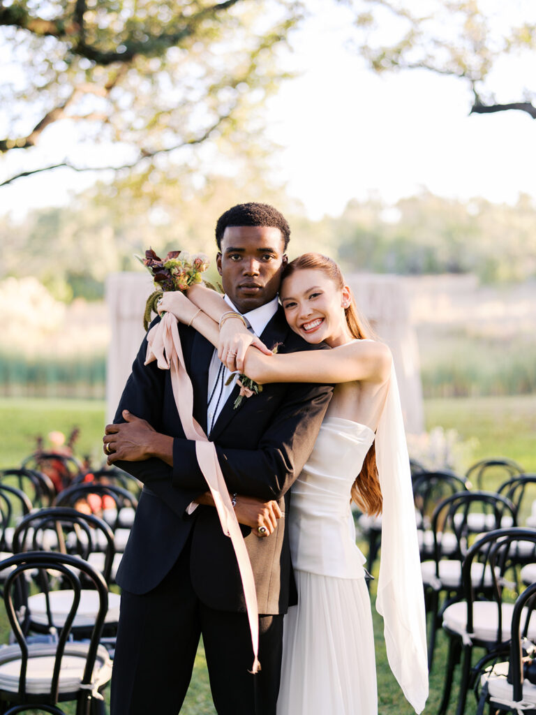 Bride and groom walking through The Addison Grove surrounded by golden fall foliage and lush florals
