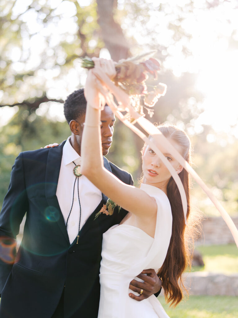 Bride and groom walking through The Addison Grove surrounded by golden fall foliage and lush florals