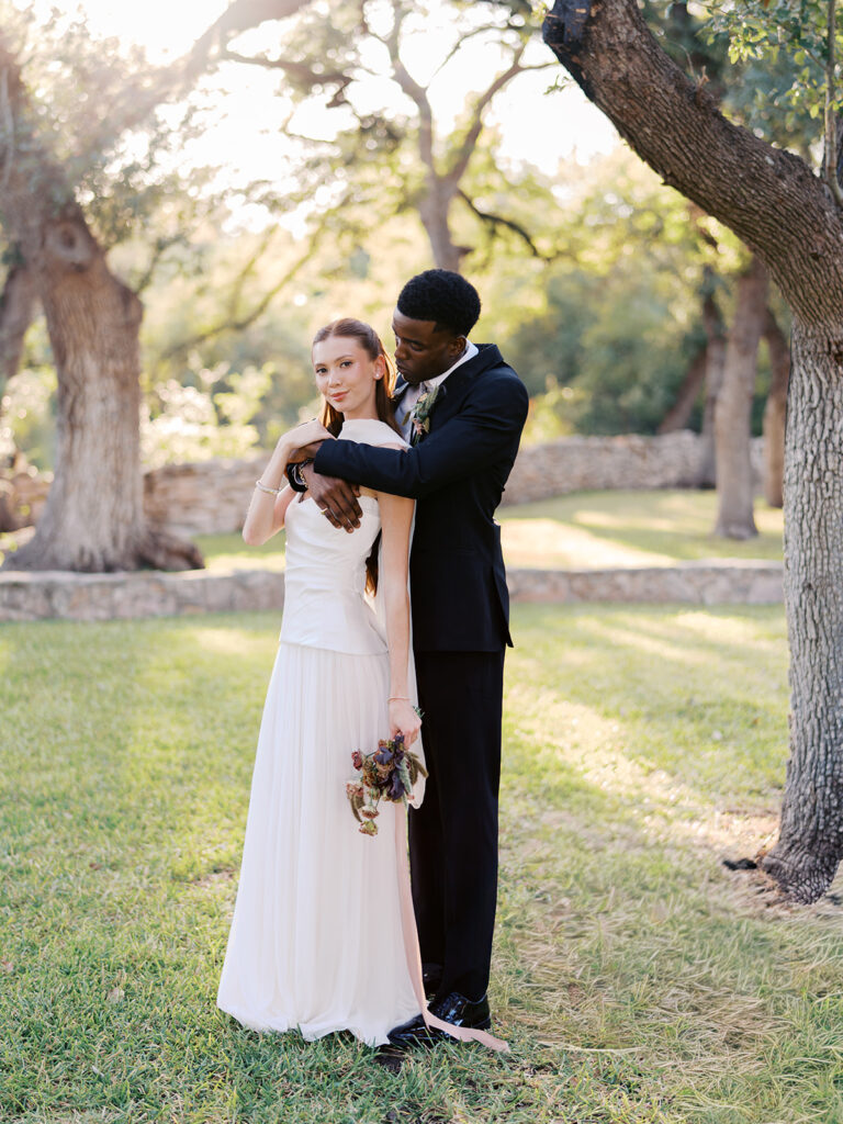Bride and groom walking through The Addison Grove surrounded by golden fall foliage and lush florals