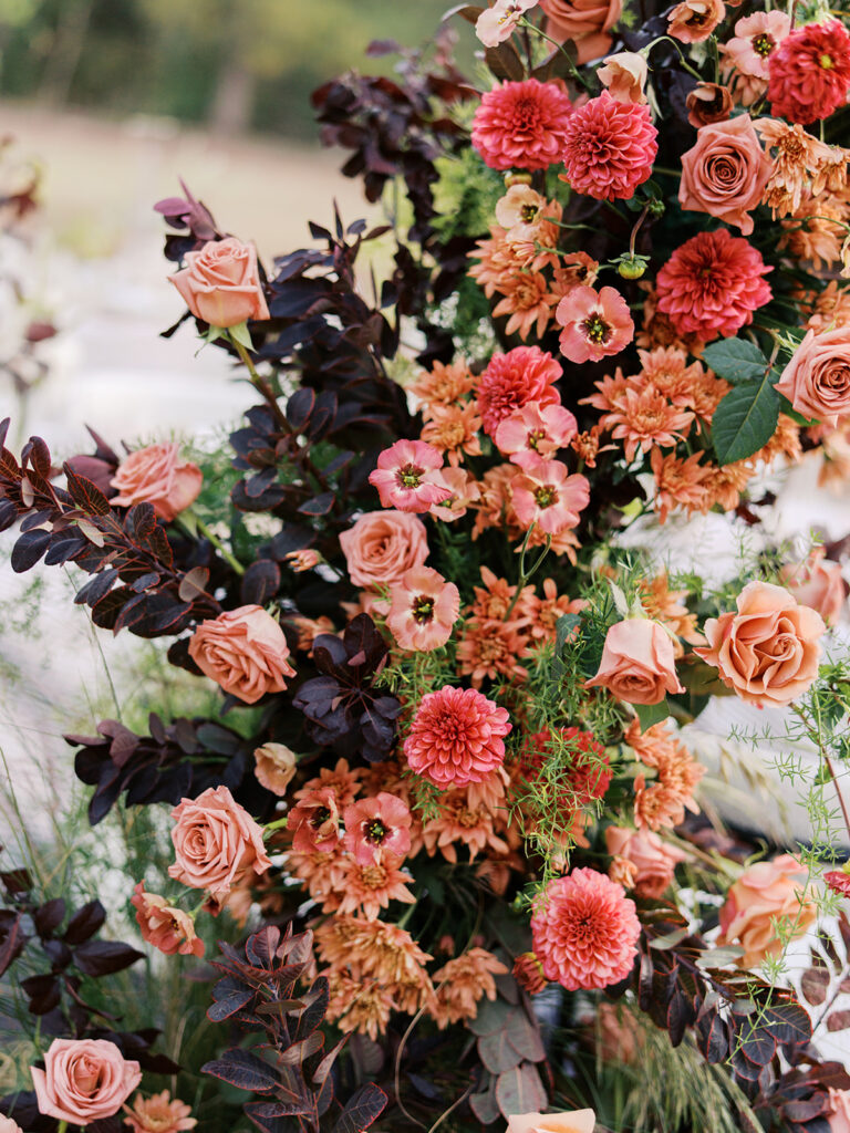 Floral installation by By Maggie Peterson with rich amber, rust, and blush tones