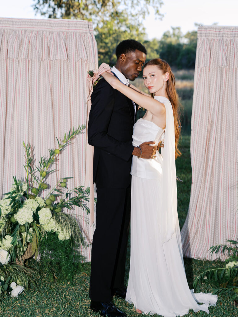 Bride and groom walking through The Addison Grove surrounded by golden fall foliage and lush florals