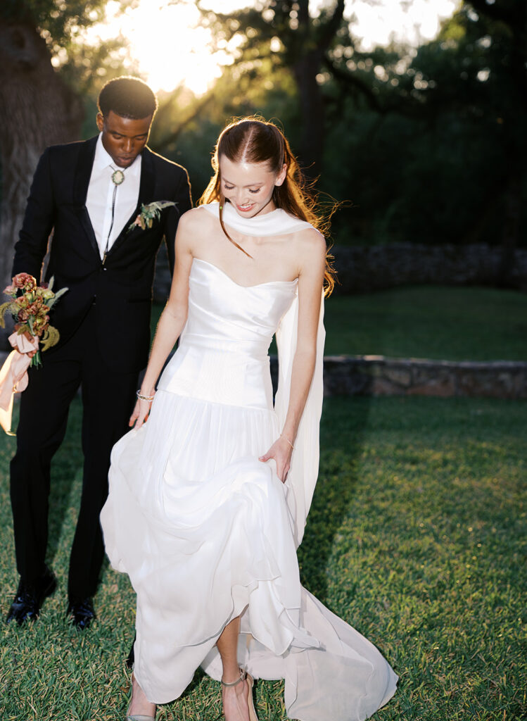 Bride and groom walking through The Addison Grove surrounded by golden fall foliage and lush florals