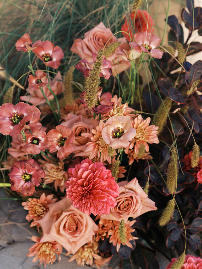 Floral installation by By Maggie Peterson with rich amber, rust, and blush tones